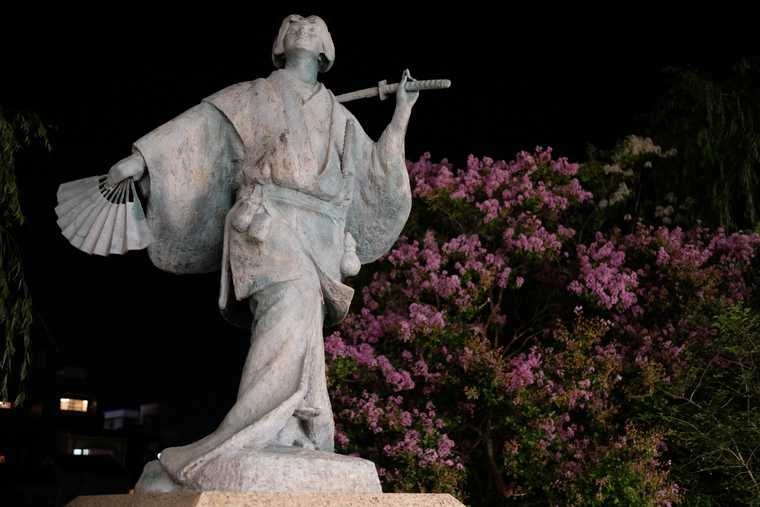 Gion statue of a Izumo no Okuni with a fan in one hand and sword in the other.